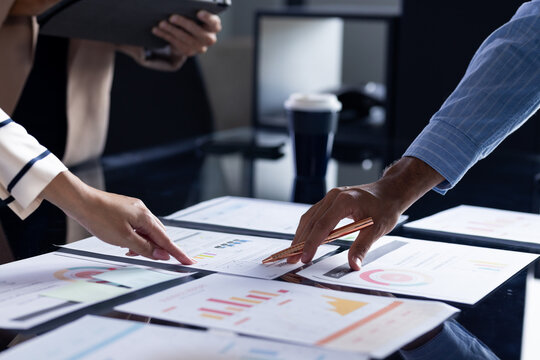 Diverse team at office reviewing business papers, woman with light hair - Powered by Adobe