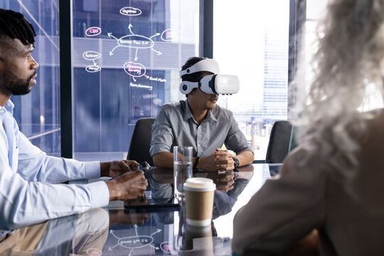 At office, diverse team at table, Asian man wearing VR headset