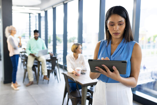 At office, diverse team working behind Caucasian woman holding tablet