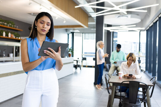 Diverse team holding tablet at office, standing before blue background