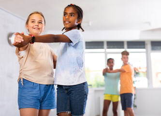 Active preteen children practicing Ballroom dances in pairs in training hall during dancing classes