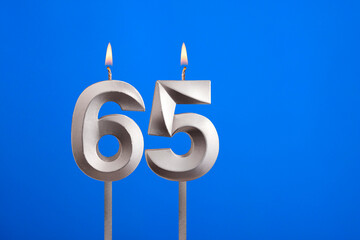 Birthday number 65 - Candle lit on blue background