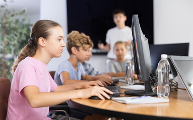 Girl student learning to use computer in group in classroom