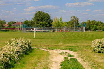 A large field with a soccer field and a house in the background