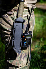 A military knife and a walkie-talkie hang on the belt of a soldier in uniform.
Military equipment,...