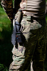A military knife and a walkie-talkie hang on the belt of a soldier in uniform.
Military equipment,...