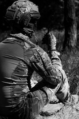 A military man in a tactical helmet and balaclava communicates on a walkie-talkie.
Military affairs, war in Ukraine. Combat actions, situational awareness
Black and white photo