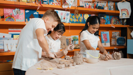 Caucasian highschool girl modeling cup of clay while looking smart boy in art class at workshop. Multicultural student playing or making cup of clay art in creative activity. Education. Edification.