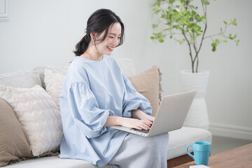 Woman using a computer sitting in the living room Image of a woman working remotely or at home Looking at a computer to search and think