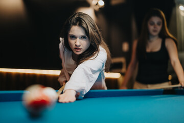 Two young women focused on winning during a fun billiards match, showcasing camaraderie and skill.