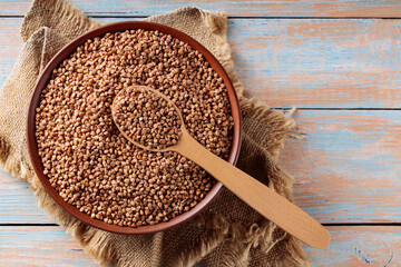 Buckwheat Grains with Wooden Spoon on Rustic Kitchen Table, Copy Space