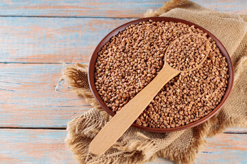Buckwheat Grains with Wooden Spoon on Rustic Kitchen Table, Copy Space