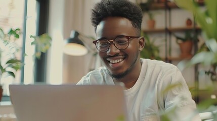Obraz premium young man using laptop and smiling at home casual working environment