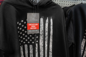 Close-up of black concealed carry sweatshirt for sale in retail store with stylized black and white...