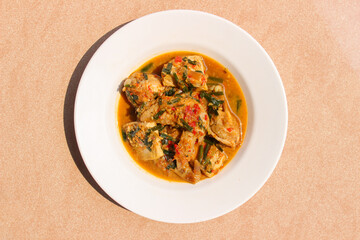 Ayam Rica Rica. Traditional dish from Manado, Indonesia, boiled chicken with the addition of tofu and using spicy spices and garnish served on a white plate
