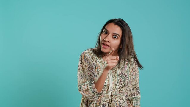Irked indian woman fighting with boyfriend, doing scolding gesturing, isolated over studio background. Outraged wife arguing with husband during conversation, doing angry hand gestures, camera A