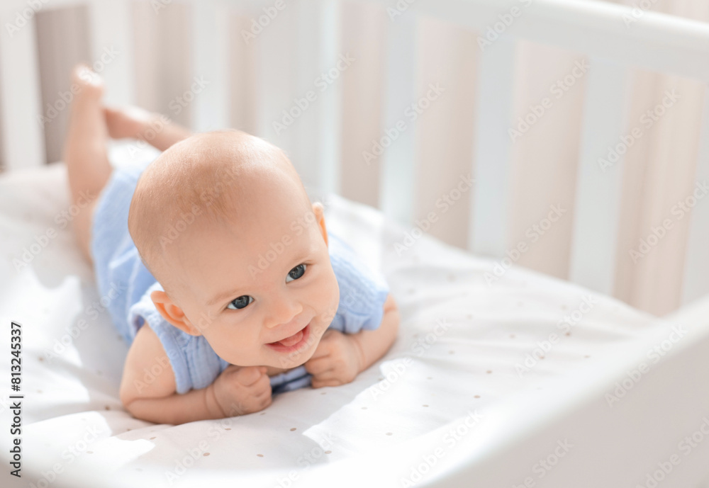 Wall mural Cute little baby lying in crib at home, space for text