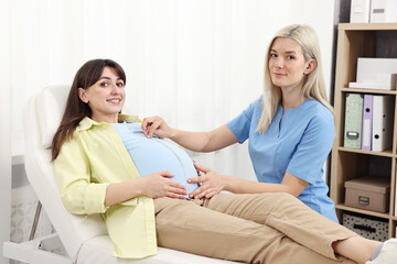 Fototapeta premium Pregnancy checkup. Doctor measuring patient's tummy in clinic