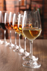 Different tasty wines in glasses on wooden table