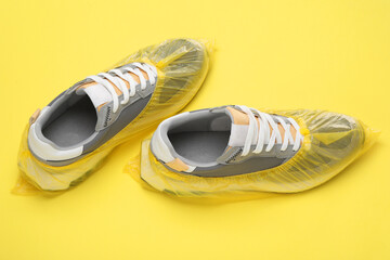 Sneakers in shoe covers on yellow background, closeup