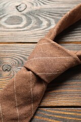 One striped necktie on wooden table, top view
