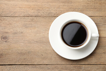Cup of aromatic coffee on wooden table, top view. Space for text