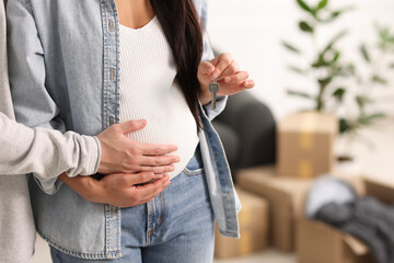 Pregnant woman and her husband with key in their new apartment, closeup. Space for text