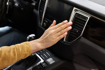 Woman checking air conditioner in her car, closeup