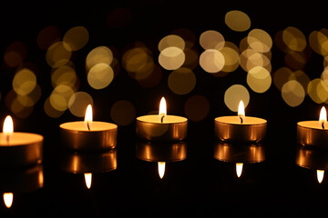 Burning candles on mirror surface in darkness, bokeh effect