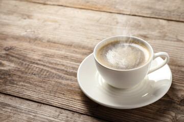 Steaming coffee in cup on wooden table. Space for text