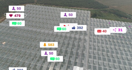 Image of social media icons floating against aerial view of solar panels in grassland