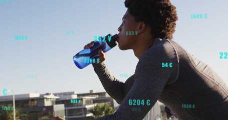 Image of changing numbers, currency symbols, african american athlete drinking water - Powered by Adobe