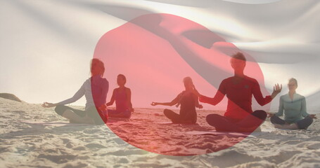 Composite image of waving japan flag against diverse group of people practicing yoga at the beach - Powered by Adobe