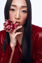 Woman with Black Hair and Red Jacket Holding Flower in Front of Her Face in Studio Portrait Photo