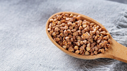 Wooden Spoon with Raw Buckwheat on Gray Linen Napkin, Copy Space