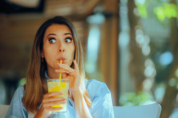 Woman Drinking a Lemonade Beverage in a Restaurant. Customer in diner sipping citrus beverage...