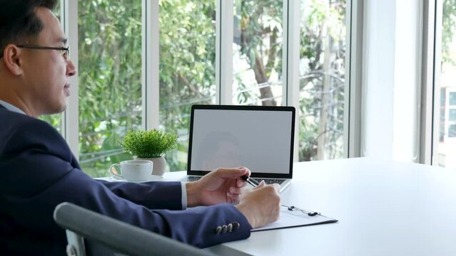Closeup businessman hands working use laptop finance business document reading report paperwork spreadsheet at office desk. Man hands type keyboard write on office note check financial graph chart