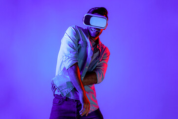 Handsome smart man dancing and moving gesture to music by using VR glasses with neon light...