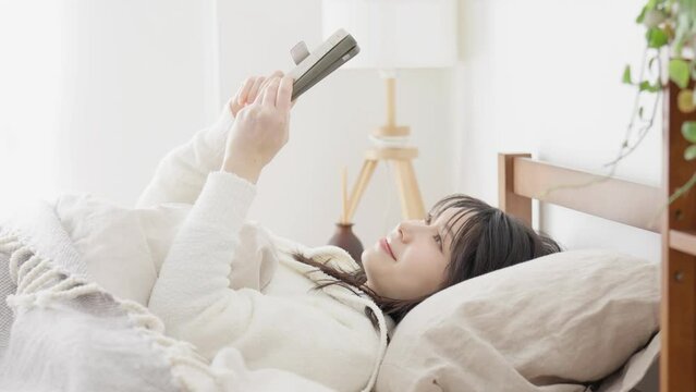 寝起きにスマホを見るアジア人女性