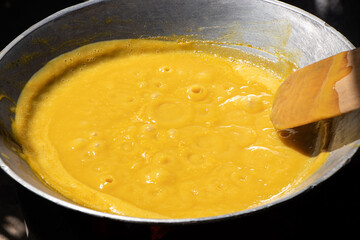 Stir-frying mango with wooden spoon in pan, prepared for stirring fruit. Making mango jam for make dried mango paste during mango season.