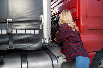 Woman truck driver checking connection to the trailer, closeup shot 