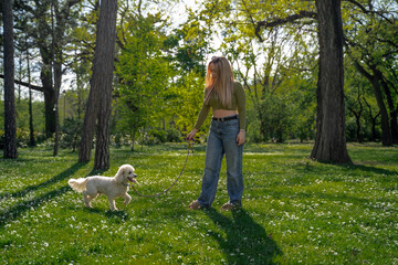 Beautiful young woman enjoying walking her dog in the park , spring time 