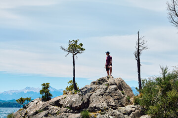 Obraz premium a young man standing on the top of a rock symbolizing unity with nature and the desire to conquer new heights