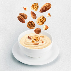 nut milk in bowl with flying nuts on white background