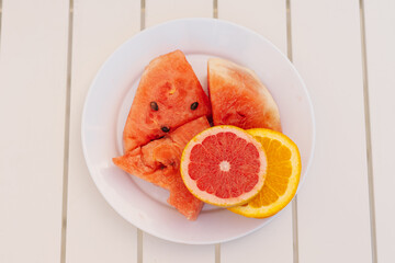 Sliced Watermelon and Citrus Fruits on a White Plate During a Sunny Day