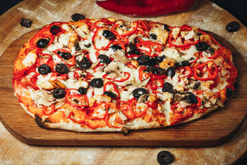 Artisanal Pizza With Olives and Peppers on Wooden Cutting Board