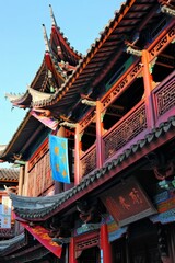 Naklejka premium A traditional Chinese opera house adorned with colorful banners, ornate carvings, and dramatic rooflines, alive with cultural performa, Generative AI