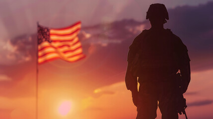 Fototapeta premium A soldier stands enjoying the sunrise with the US flag flying next to him. National holiday, flag day, veterans day, memorial day, independence day, patriot day concept.