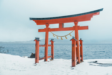 Red Japanese Torii gate of Goza no Ishi Shrine at lake tazawa in winter, located in Semboku city, Akita Prefecture, northern Japan. Landmark and famous for tourists attractions in Tohoku region, Japan