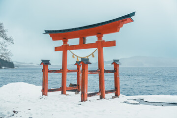 Red Japanese Torii gate of Goza no Ishi Shrine at lake tazawa in winter, located in Semboku city,...